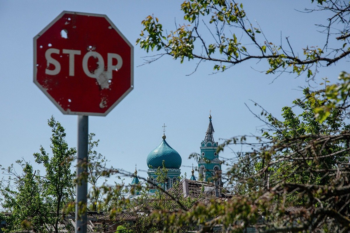 Разрушенный храм на фоне обстрелянного дорожного знака в Козинке, май 2024 года. Фото: Анатолий Ольшанский