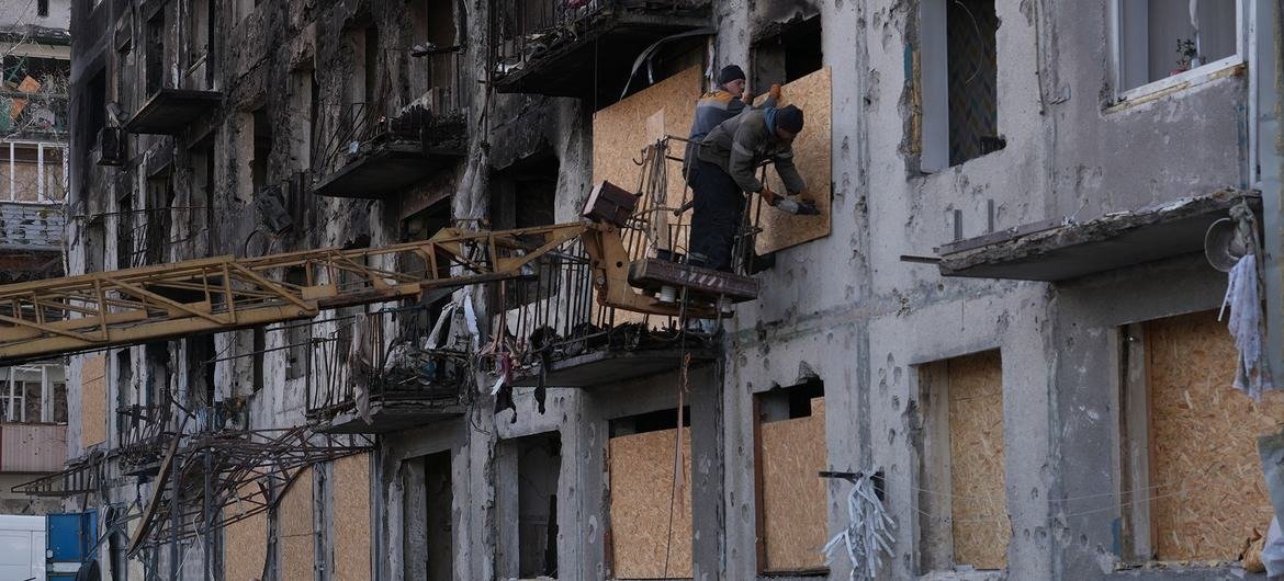 Рабочие закрепляют фанерные доски поверх разбитых окон жилого дома, поврежденного ракетным ударом на востоке Украины. Фото: © UNICEF/Oleksii Filippov