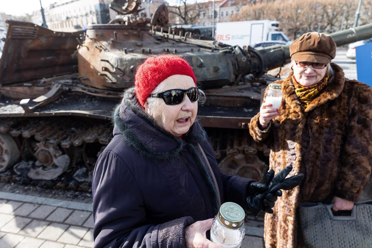 Люди несут свечи к подбитому российскому танку, выставленному в Вильнюсе. Фото: BNS
